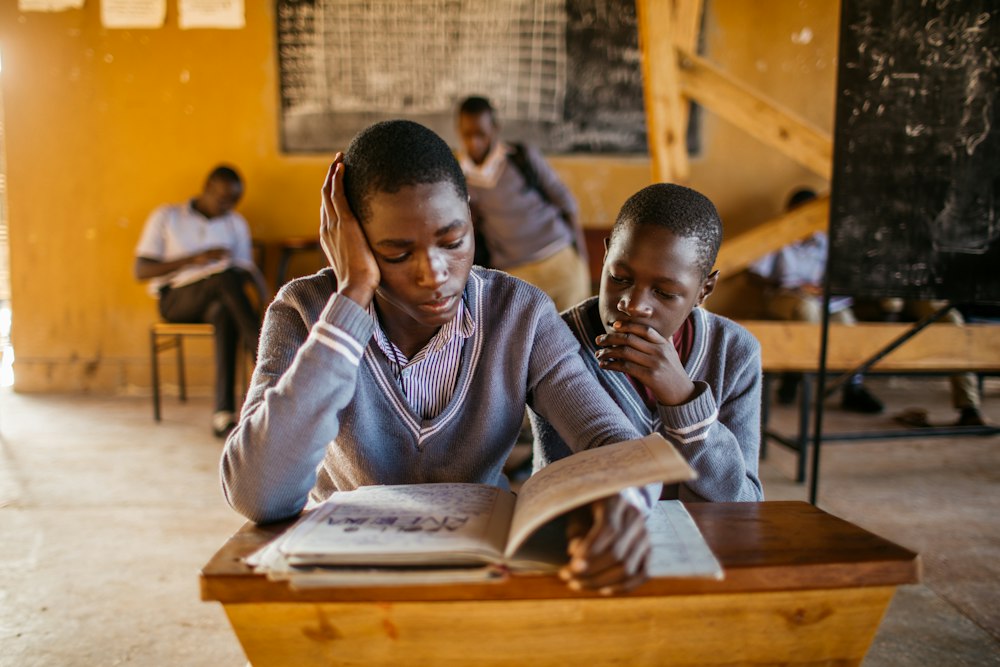 Two pupils reading a book together at a desk